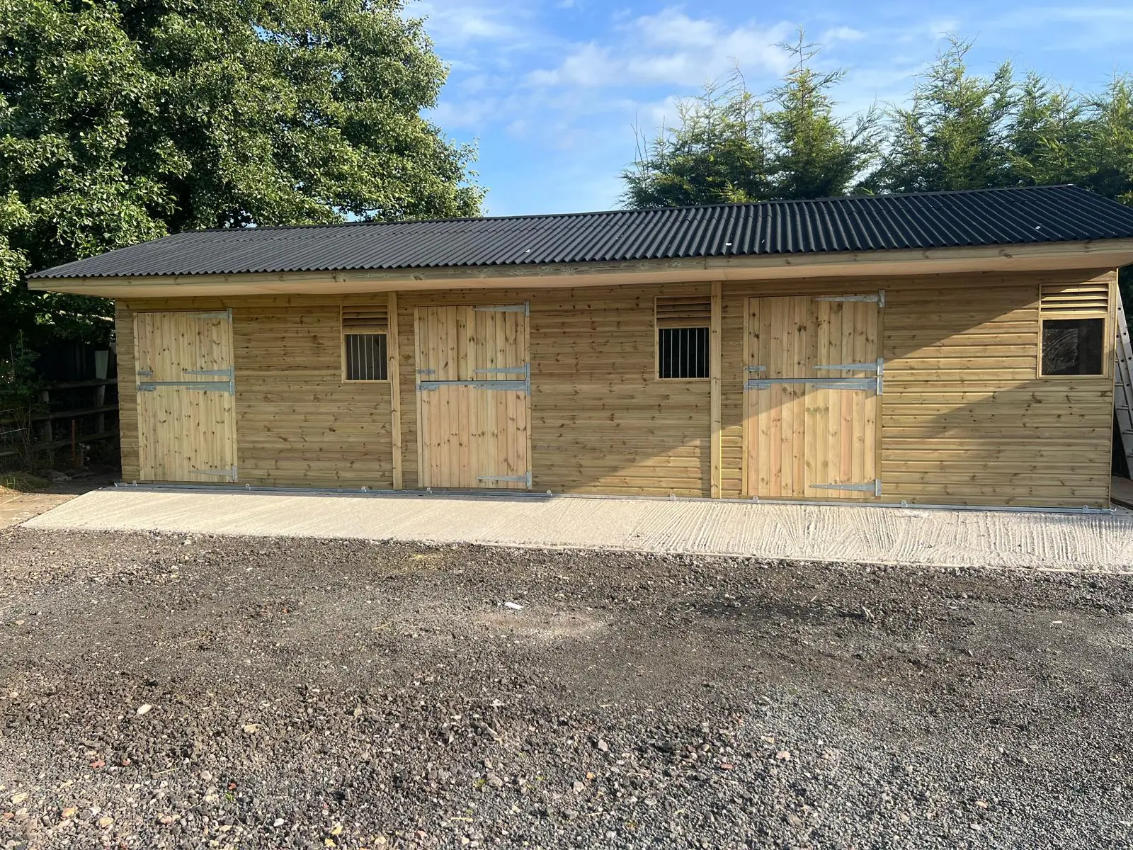 Front view of a timber stable block with three individual stable fronts
